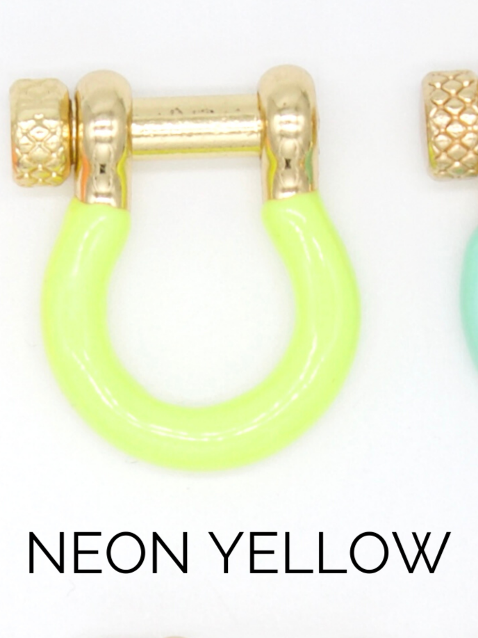 A neon yellow shackle earring with gold hardware rests against a white background.