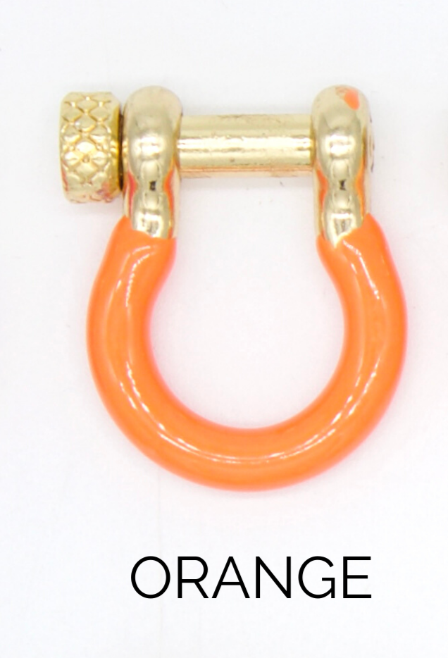 A vibrant orange enamel shackle charm with gold hardware sits against a white background.