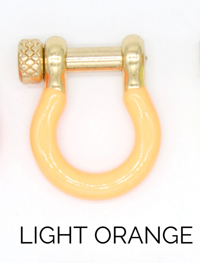 A light orange horseshoe shackle earring with a gold screw pin rests against a plain white background.