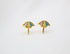 A pair of gold stud earrings shaped like colorful little umbrellas rests on a white background.