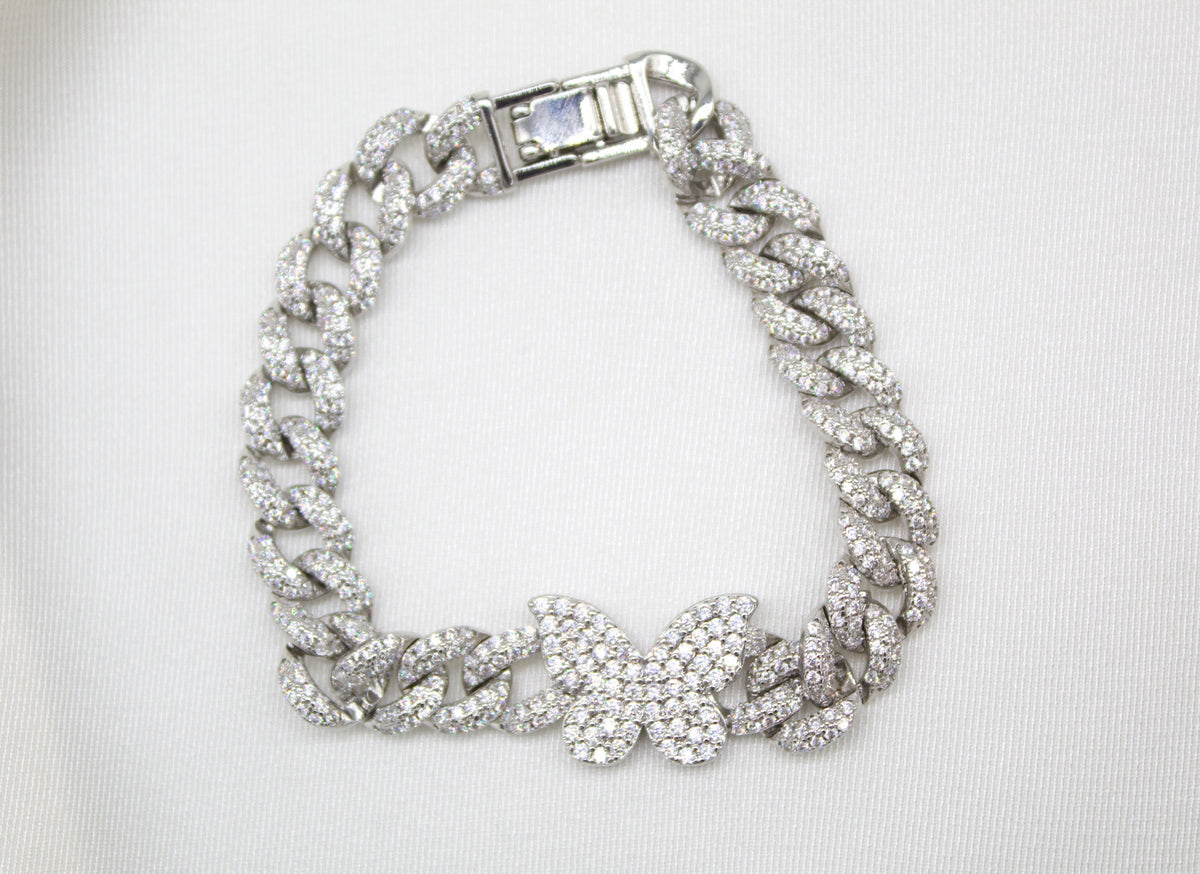 A sparkling iced-out cuban link bracelet features a diamond-paved butterfly pendant against a white background.
