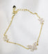A delicate gold chain bracelet features three pavé crystal-encrusted butterfly charms resting against a white fabric background.