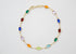 A delicate gold chain bracelet features an array of colorful multi-gemstone stations against a neutral white background.