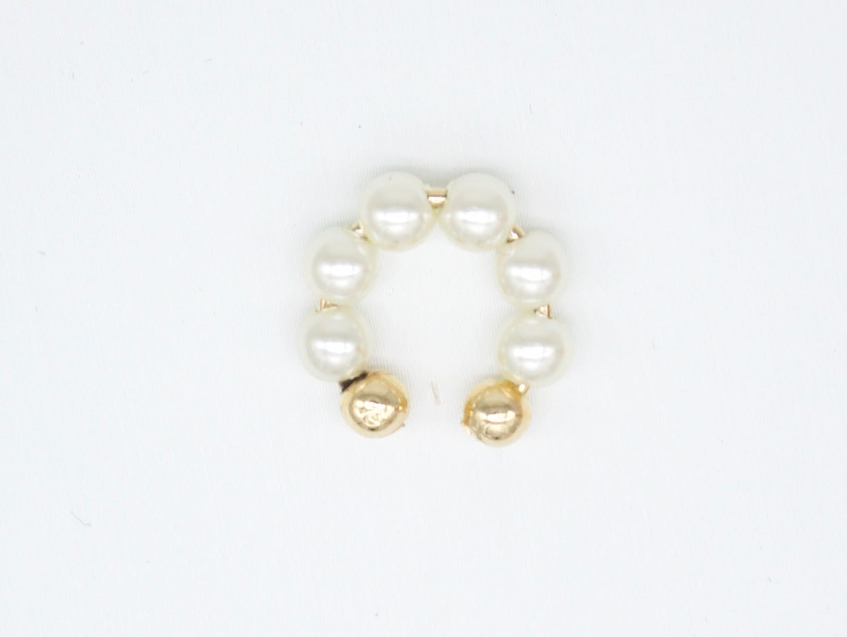A gold pearl ear cuff rests on a clean white background.