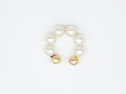 A gold pearl ear cuff rests on a clean white background.