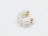 A gold ear cuff features a double band of lustrous faux pearls against a clean white background.