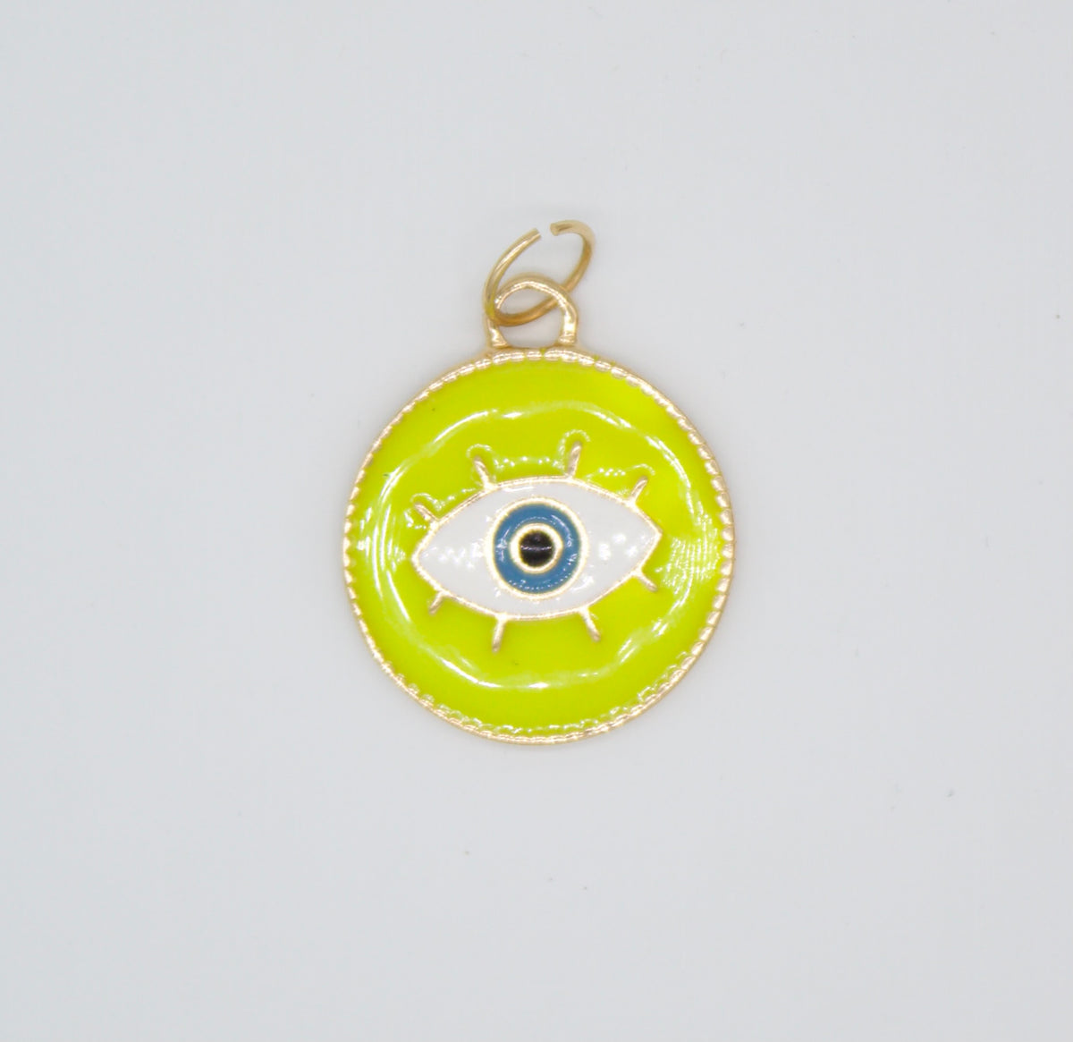 A round chartreuse and gold pendant displays a stylized evil eye charm with blue, white, and black enamel.