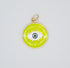A round chartreuse and gold pendant displays a stylized evil eye charm with blue, white, and black enamel.