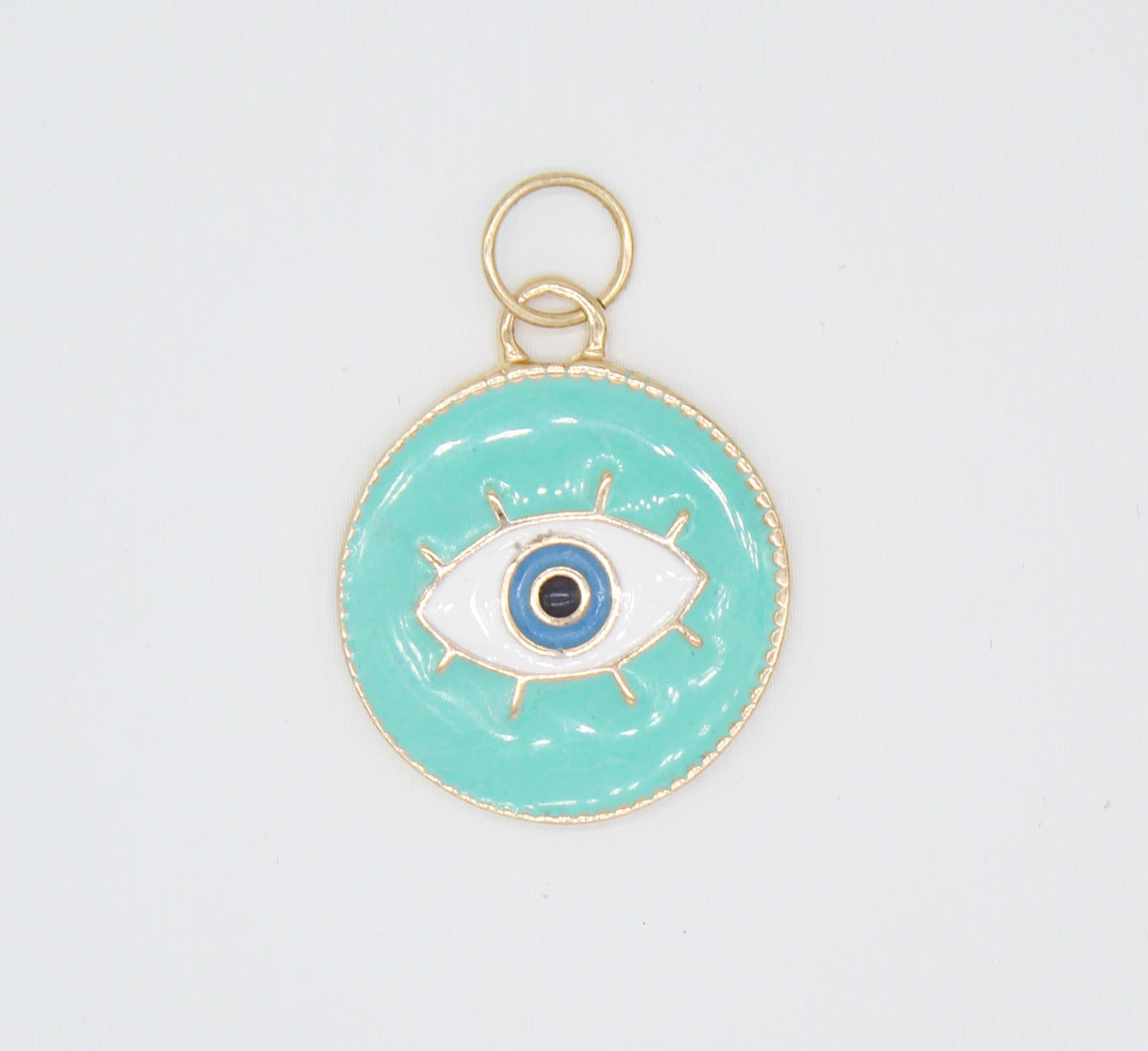 A gold-rimmed teal enamel evil eye charm features a detailed blue and white eye design with a hanging loop.