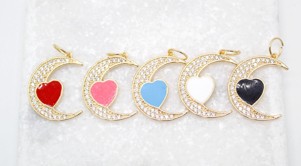 Five gold crescent moon pendants paved with cubic zirconia display colorful enamel hearts in red, pink, blue, white, and black against a white background.