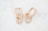 A pair of rose gold interlocking chain link earrings featuring pavé-set diamonds rests on a textured white surface.