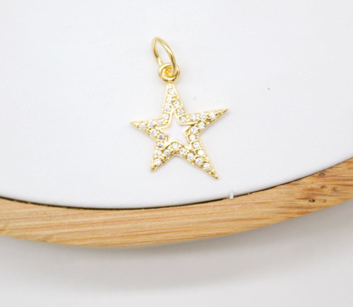 A sparkling gold star pendant encrusted with tiny diamonds rests on a white display surface.