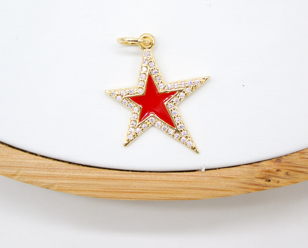 A gold star charm inlaid with sparkling cubic zirconia crystals and vibrant red enamel rests against a light background.