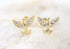 A pair of gold dove earrings with sparkling cubic zirconia stones rest on a light background.