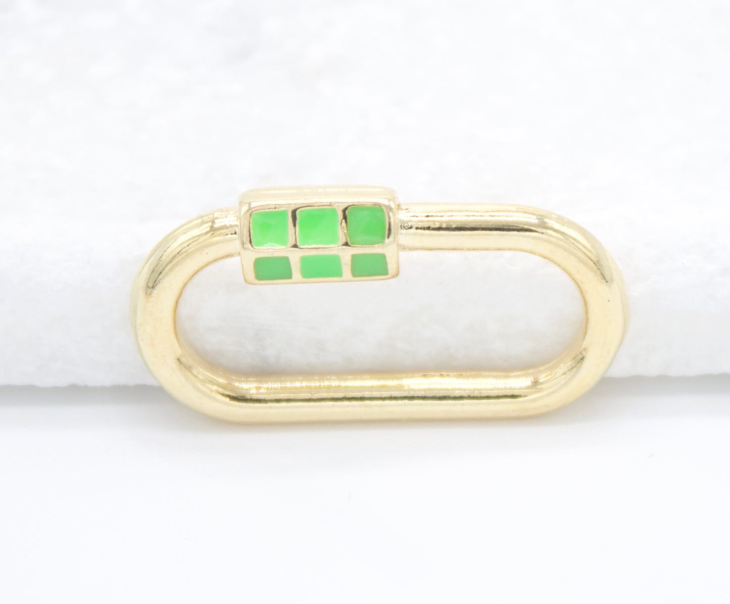 A gold charm connector features a clasp accented with bright green enamel squares.