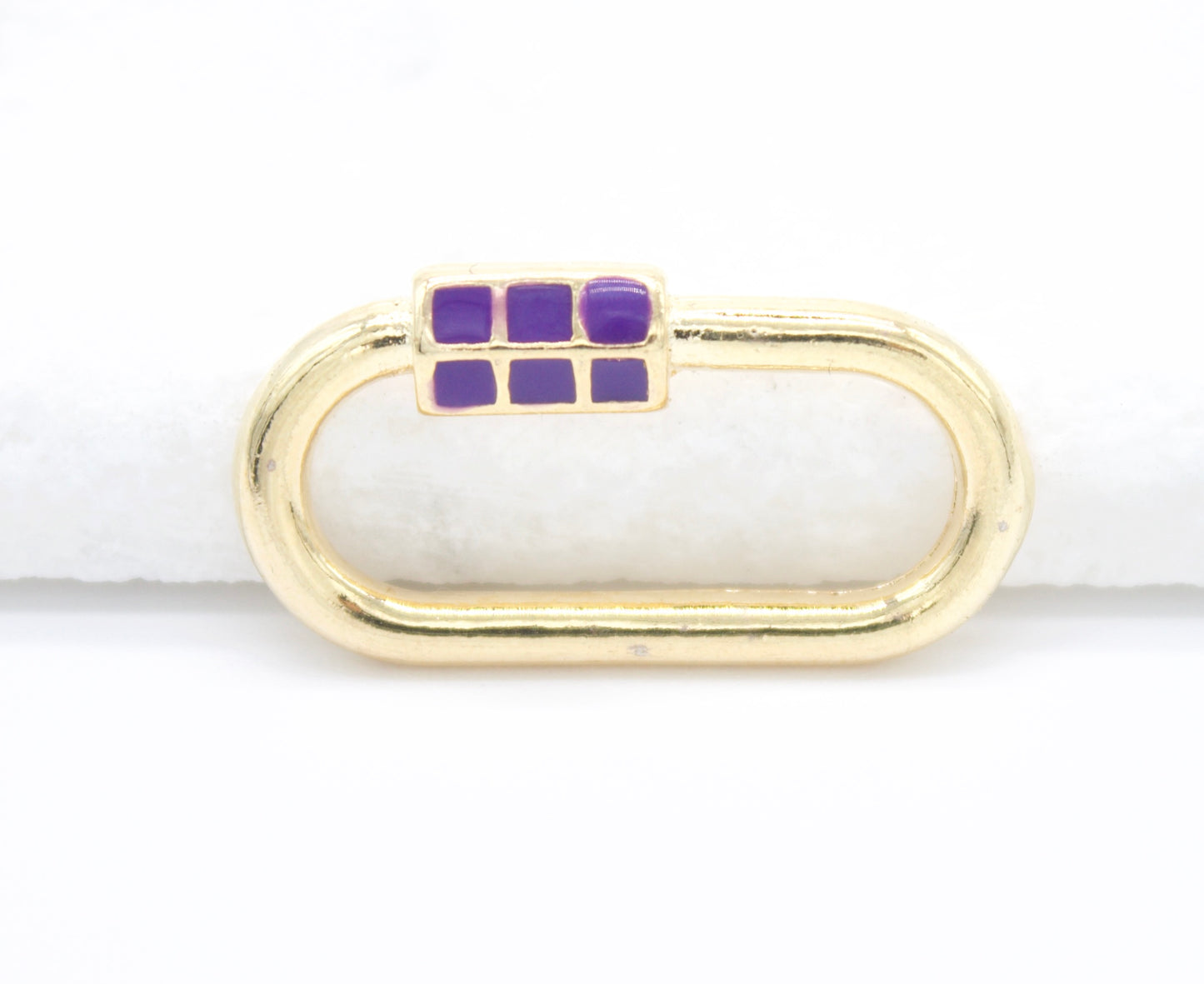 A gold oval carabiner jewelry clasp features vibrant purple enamel square details along its screw gate against a clean white background.