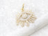 A sparkling gold evil eye pendant embellished with cubic zirconia crystals rests on a textured white surface.