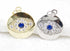 A gold and a silver evil eye pendant feature sparkling cubic zirconia pavé stones surrounding a central deep blue sapphire crystal.