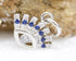 A silver evil eye charm sparkles with pave-set white and blue cubic zirconia stones against a textured stone backdrop.