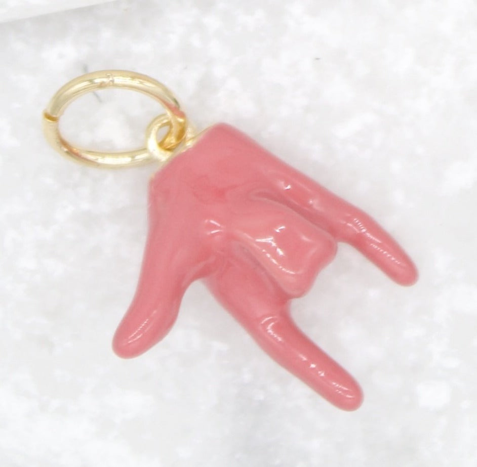 A shiny gold jump ring holds a glossy pink enamel hand charm shaped in the classic rock-on gesture.
