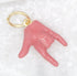 A shiny gold jump ring holds a glossy pink enamel hand charm shaped in the classic rock-on gesture.