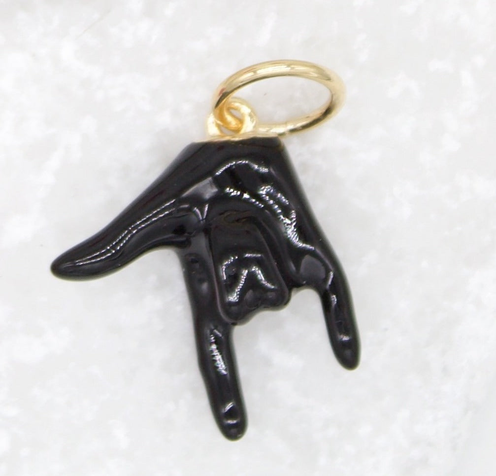 A black enamel hand charm featuring the I love you sign language gesture hangs from a gold jump ring.