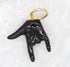 A black enamel hand charm featuring the I love you sign language gesture hangs from a gold jump ring.