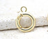 A shiny gold spring ring clasp rests on a textured stone surface, showcasing its round shape and secure closure mechanism.