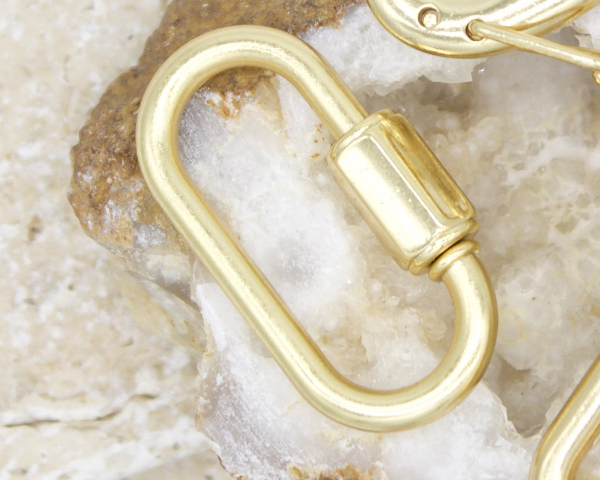 A gold oval lock clasp rests on a textured white quartz crystal background.