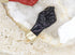 A glossy black fist charm with a gold cap rests on a sparkling white crystal cluster.