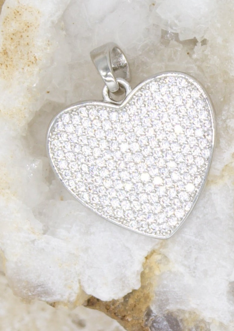 A sparkling pavé-set diamond heart pendant rests inside a textured white quartz geode.