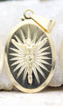 A gold crucifix pendant features an oval medallion depicting Jesus on the cross against a background of radiating sunburst rays.