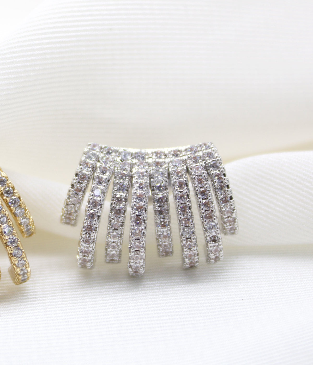 A silver multi-band ear cuff sparkles brilliantly with pavé-set cz stones against a soft white fabric background.