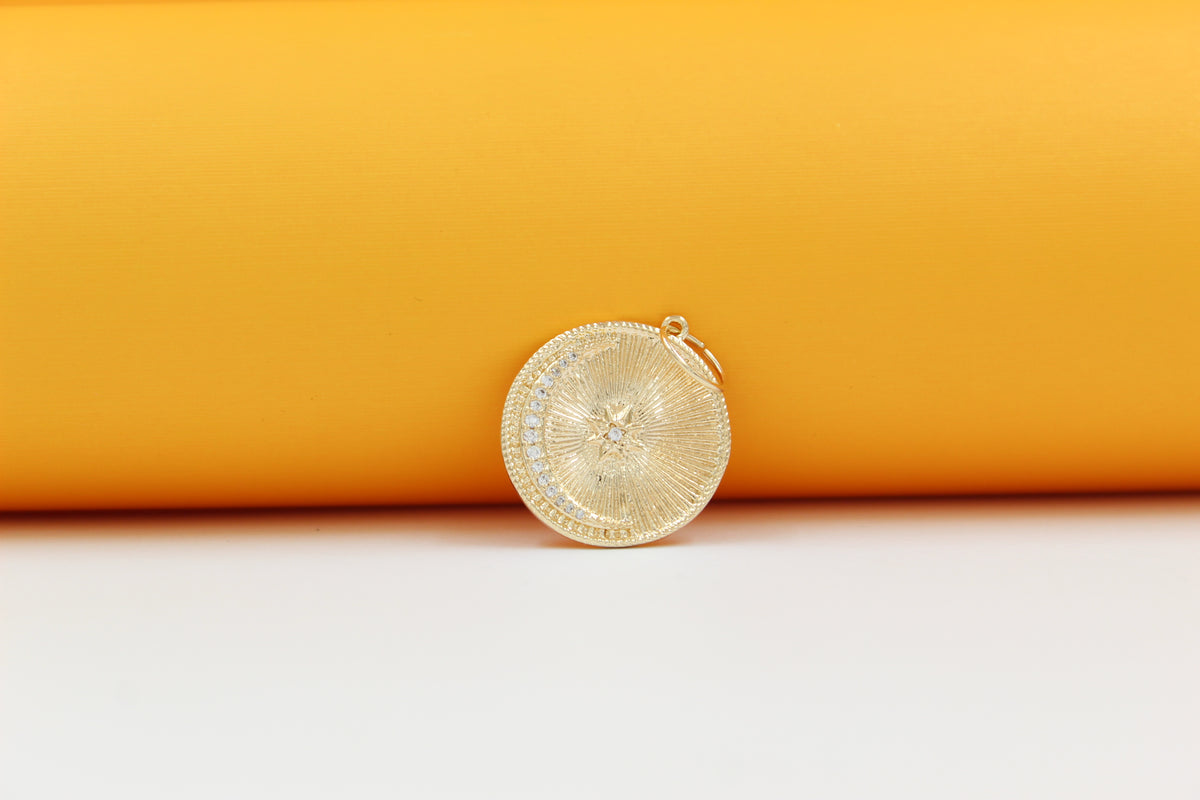 A round gold pendant featuring a crescent moon and star design rests against a vibrant orange backdrop.