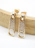 A pair of gold zipper pull earrings encrusted with sparkling cubic zirconia stones rests against a wooden display.