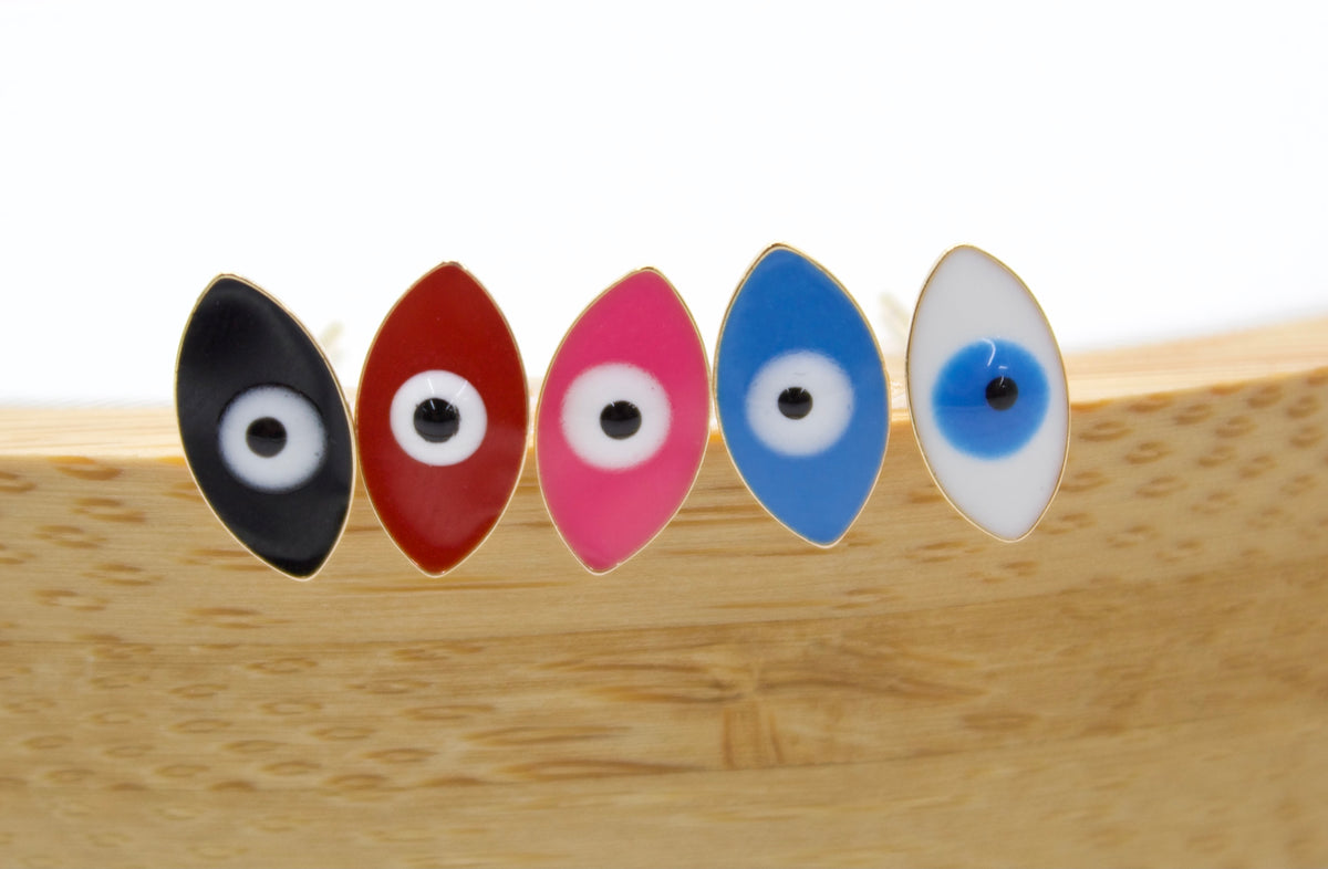 Five colorful evil eye enamel stud earrings in black, red, pink, blue, and white display upright on a wooden surface.