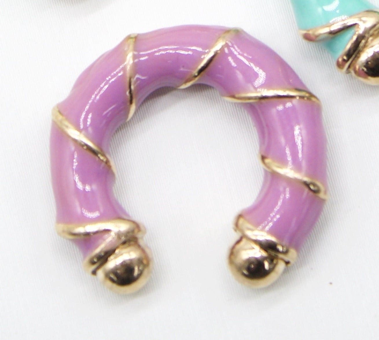 A lavender enamel and gold hoop earring features a textured bamboo design.
