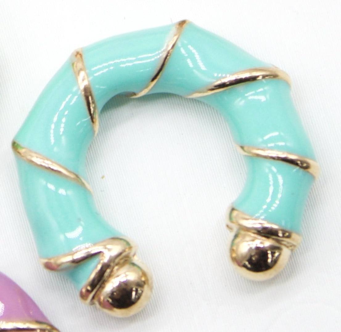 A chunky turquoise enamel hoop earring features polished gold accents spiraling along its bamboo-inspired shape.