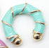 A chunky turquoise enamel hoop earring features polished gold accents spiraling along its bamboo-inspired shape.