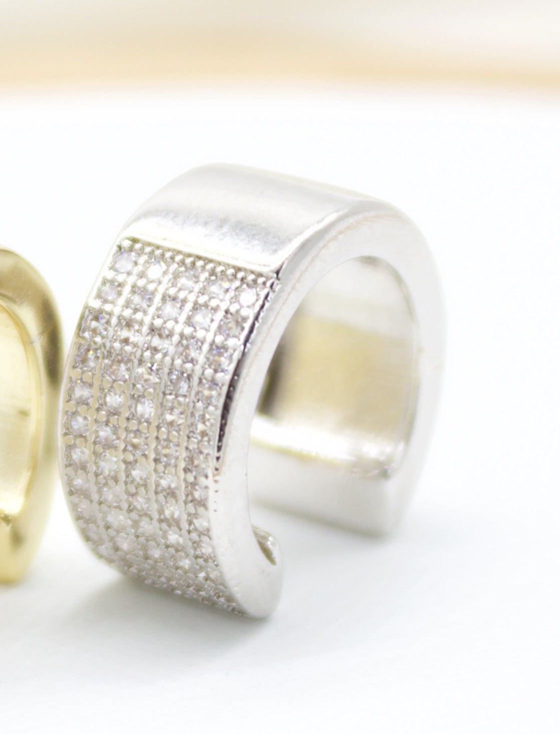 A wide silver ear cuff encrusted with sparkling pave stones sits against a white background.