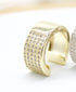 A thick gold ear cuff sparkles with rows of tiny, inlaid crystals on a white surface.