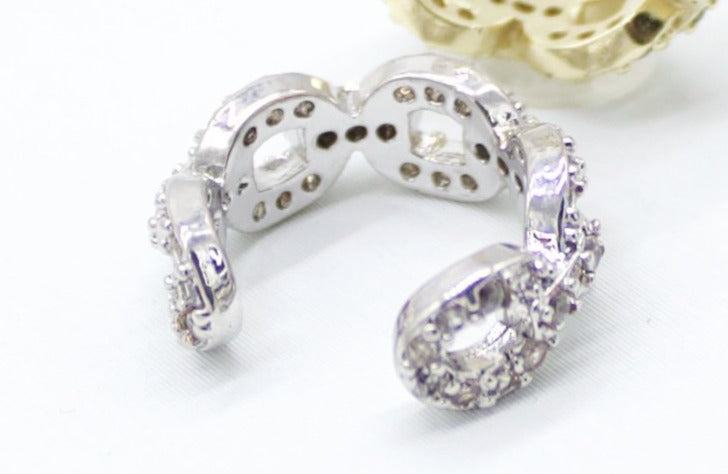 A silver infinity ear cuff sparkles with small pavé-set stones against a light background.