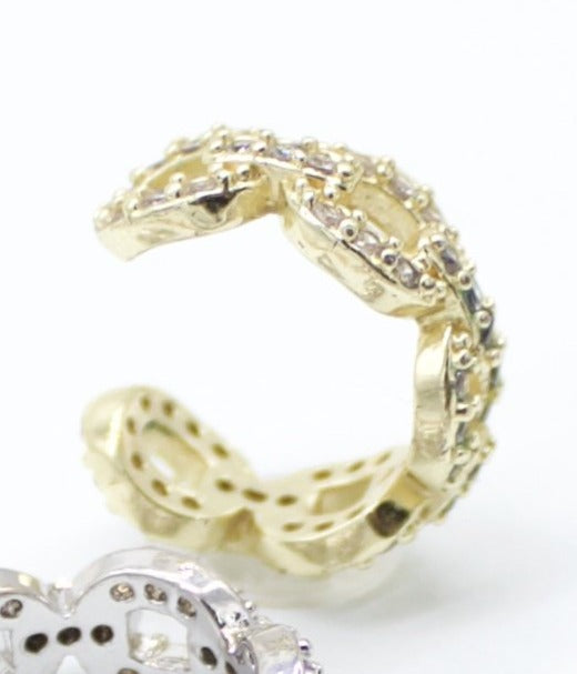 A gold pavé ear cuff sparkles brightly against a clean white background.