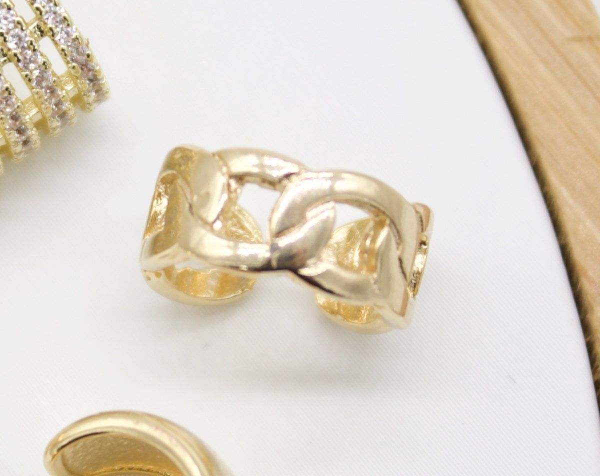 A polished gold chain-link ear cuff rests on a white display surface.