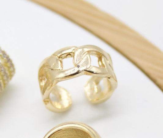 A stylish gold chain link ear cuff rests on a clean white surface.