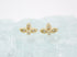 A pair of gold butterfly stud earrings rests on a textured light surface.