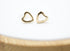 A pair of polished gold heart-shaped stud earrings rests neatly on a clean white surface.