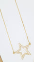 A delicate gold star pendant necklace sparkles with embedded cubic zirconia stones against a neutral background.