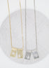 Two gold and two silver rectangular pendant necklaces with religious cut-out designs rest on a textured grey circular display.
