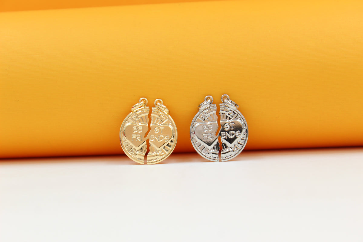 Two metallic "Best Friends" split heart pendants rest side-by-side on a vibrant orange and white background, with the left pendant in gold and the right in silver.